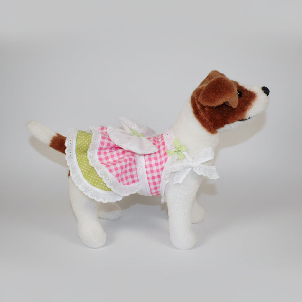 Stuffed dog toy wearing a checkered dress with a bow on a beige couch.