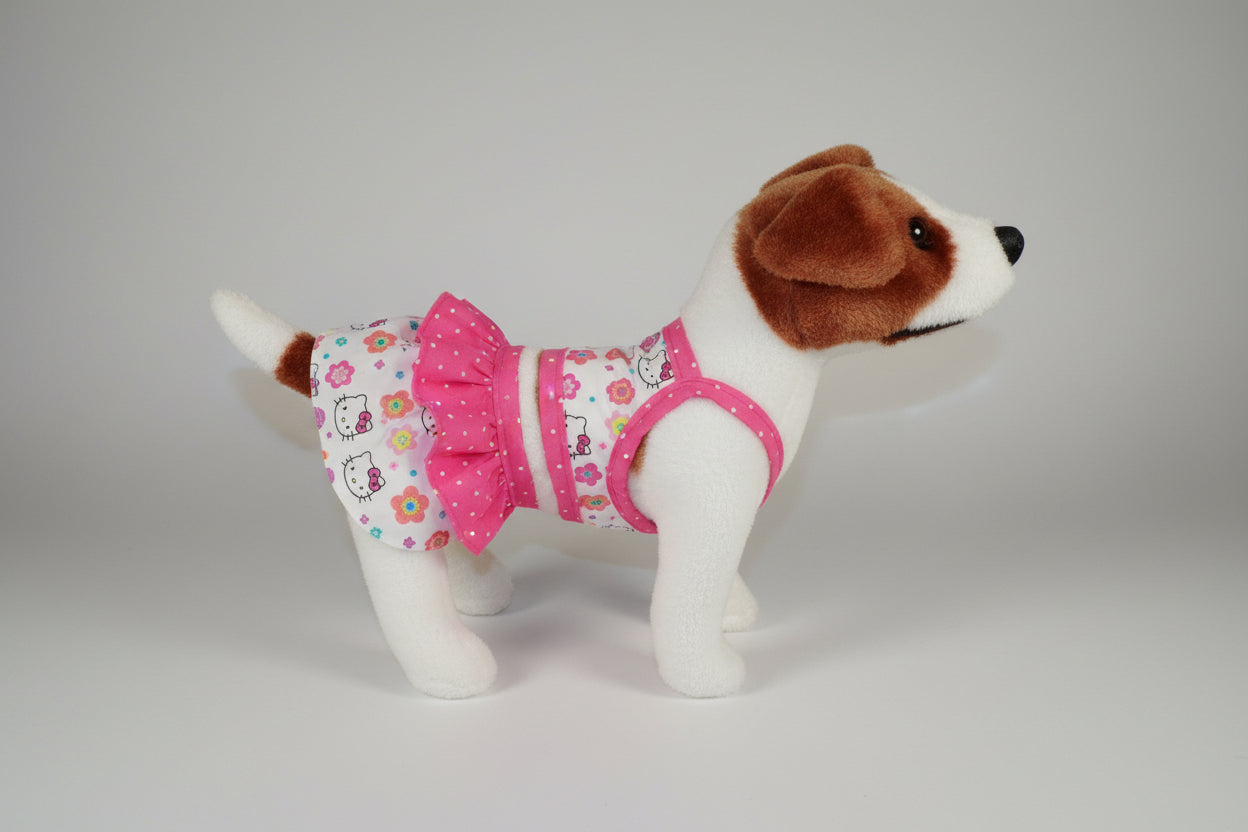 Stuffed dog toy wearing a pink dress with floral patterns on a beige couch.