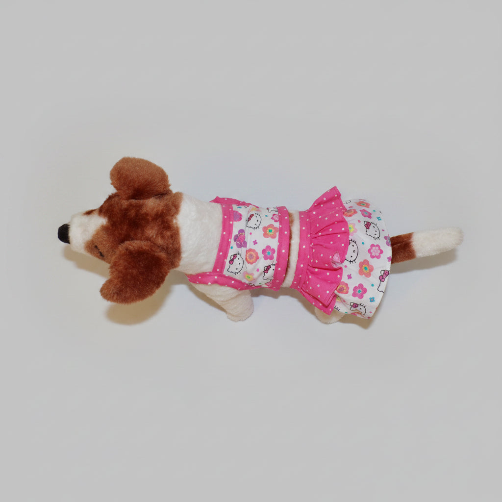 Stuffed dog toy with a pink and white dress on a beige couch