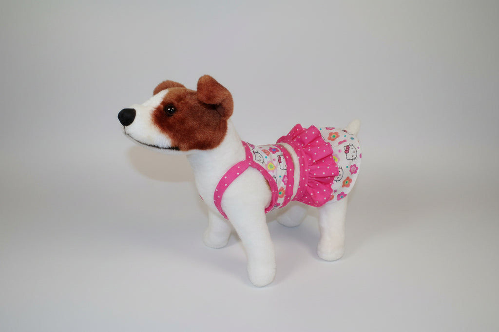 Stuffed dog wearing a pink dress with floral patterns on a beige couch.