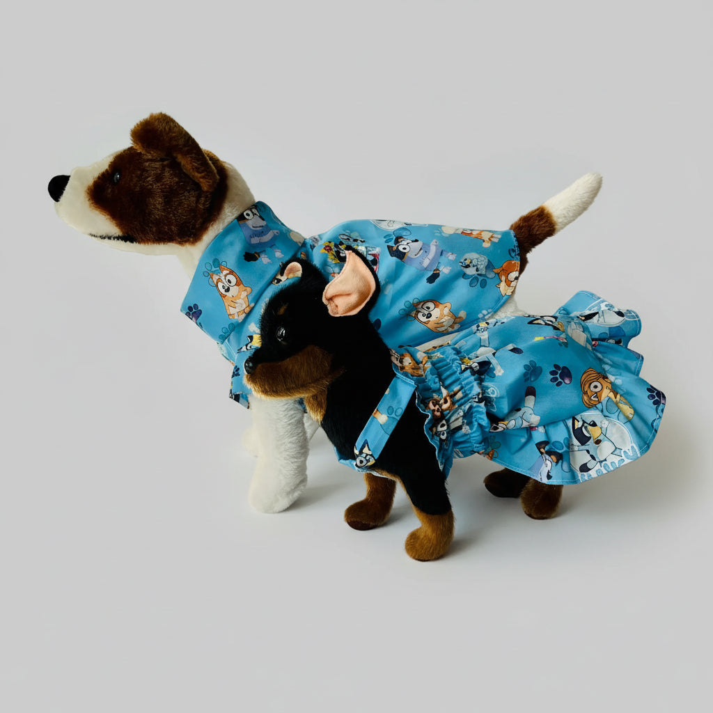 Dog wearing a blue dress with cartoon characters on a white background