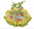 Colorful children's dress with ruffled yellow skirt and fruit pattern on a white background