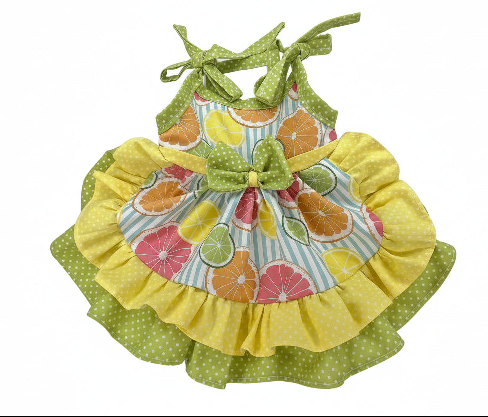 Colorful children's dress with ruffled yellow skirt and fruit pattern on a white background