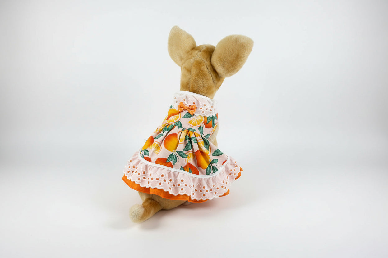 Stuffed animal wearing a dress with an orange pattern on a white background