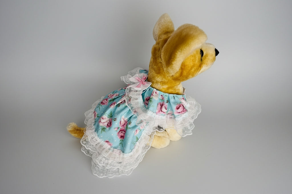 Stuffed animal in a floral dress on a pink surface