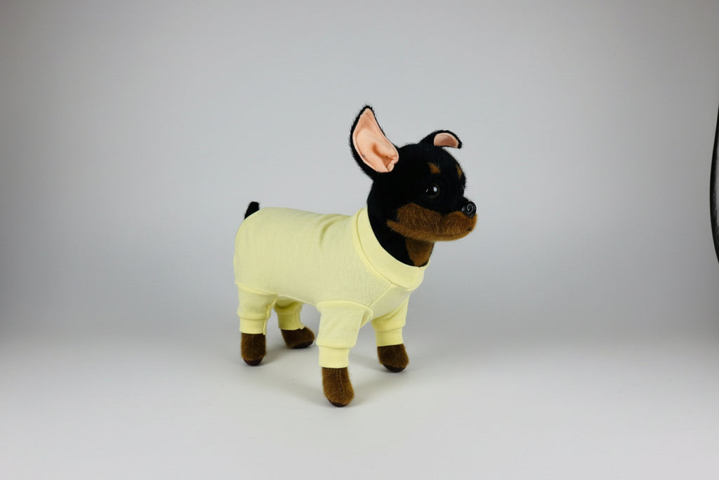 Stuffed dog toy wearing a yellow outfit on a white background