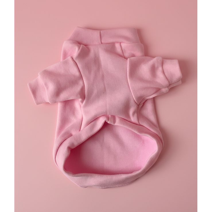 Pink dog shirt on a white bedspread