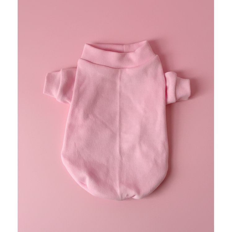 Pink dog sweater on a white bedspread