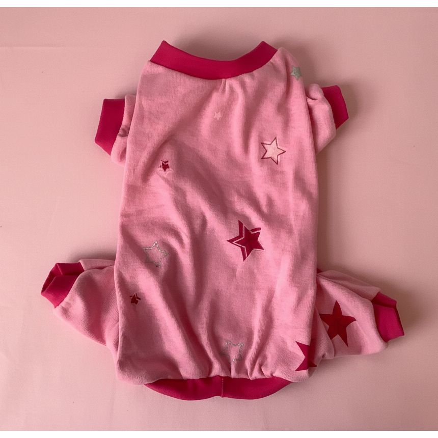 Pink baby dog pajamas with star patterns on a white blanket
