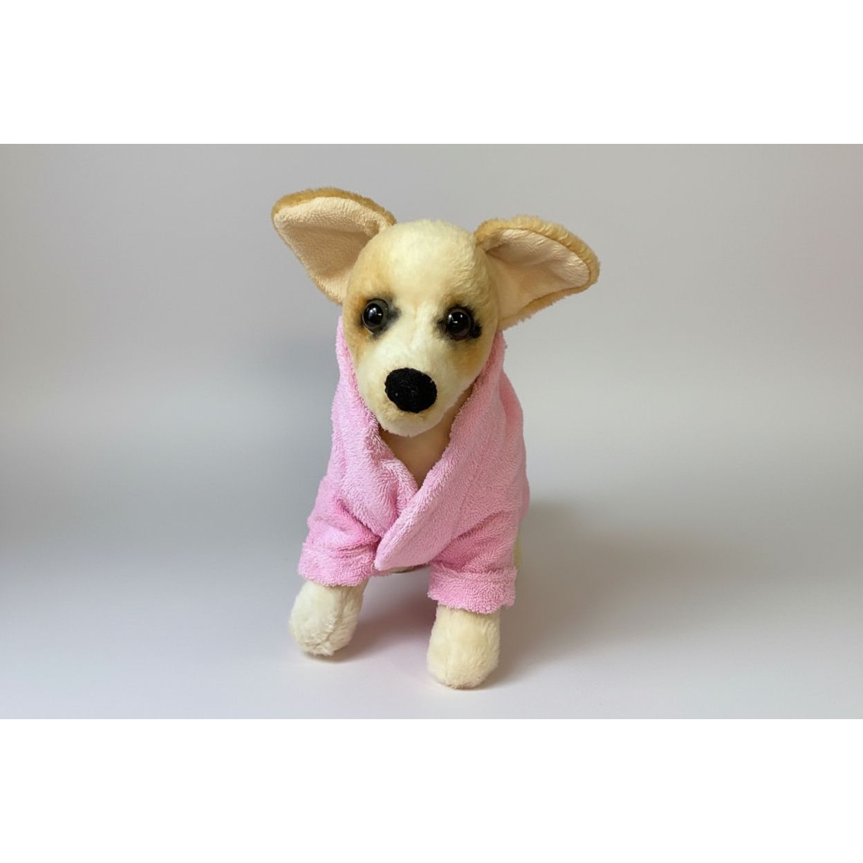 Stuffed dog toy wearing a pink robe on a white background