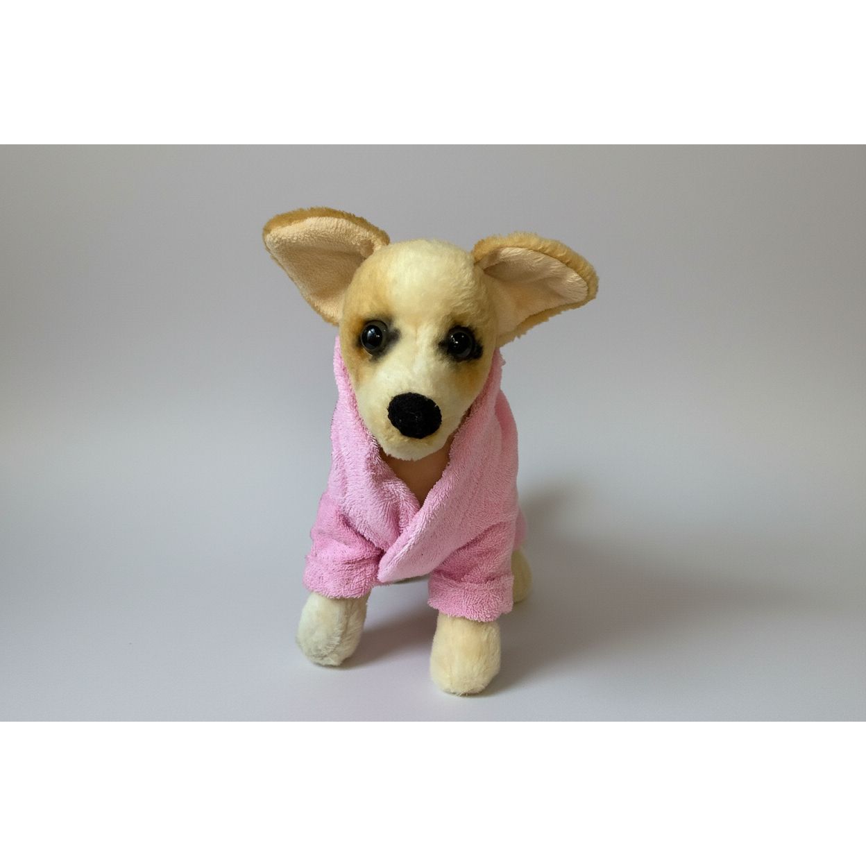 Stuffed dog toy wearing a pink robe on a white background