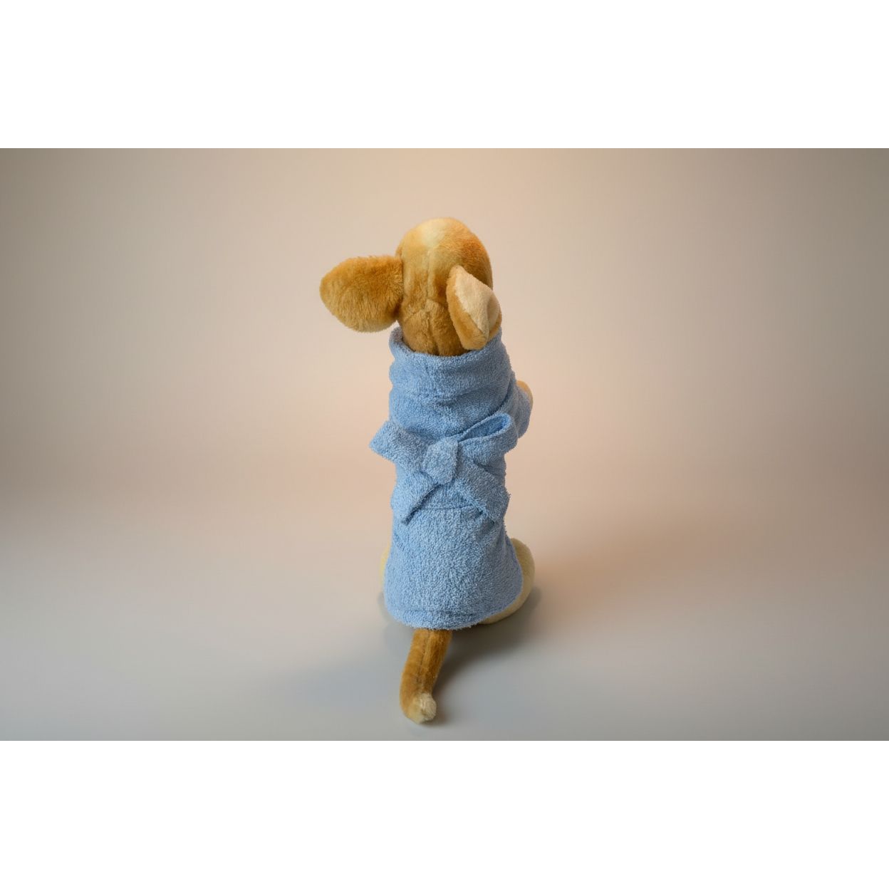 Stuffed dog toy wrapped in a blue towel on a white surface