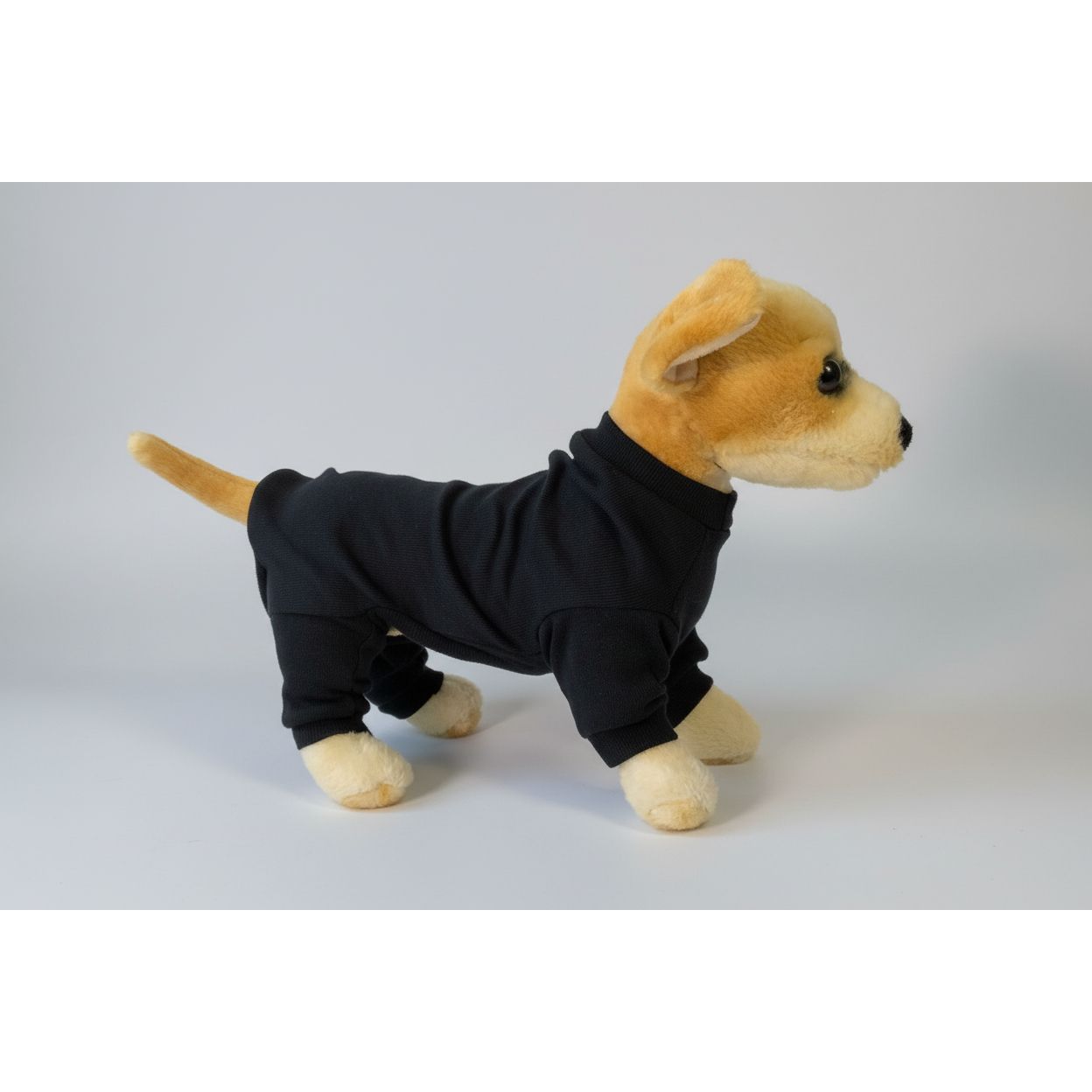 Plush dog wearing a black pajama outfit on a white background