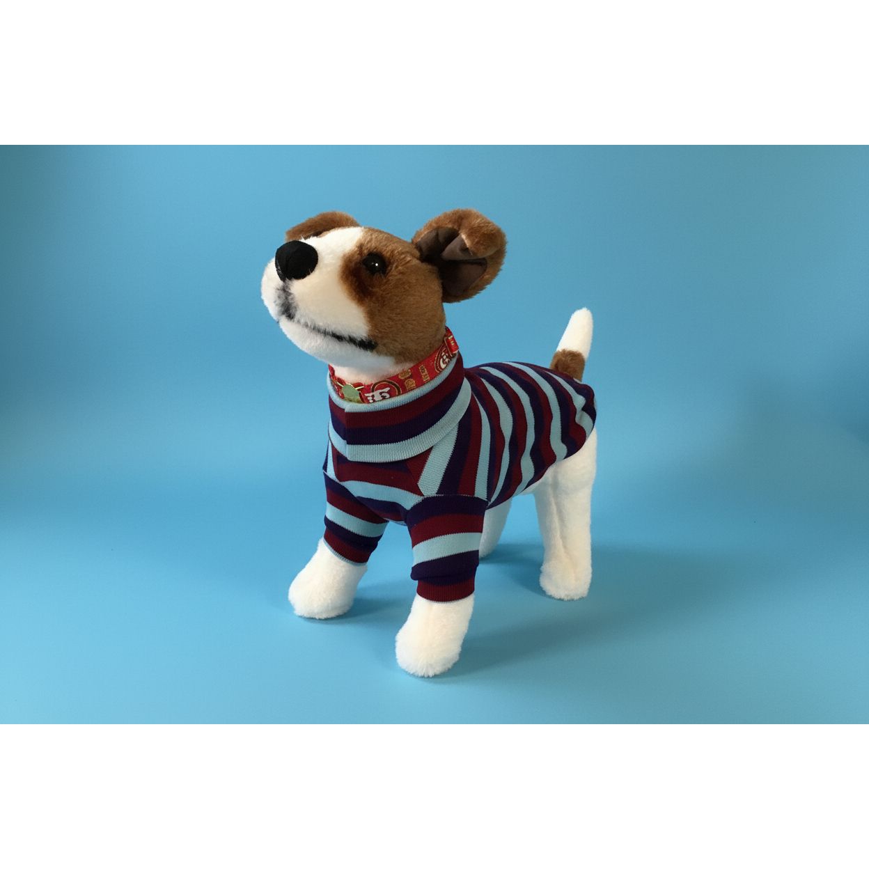 Stuffed dog toy wearing a striped turtleneck sweater outfit on a white background