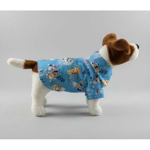 Dog wearing a bluey patterned shirt on a white bed