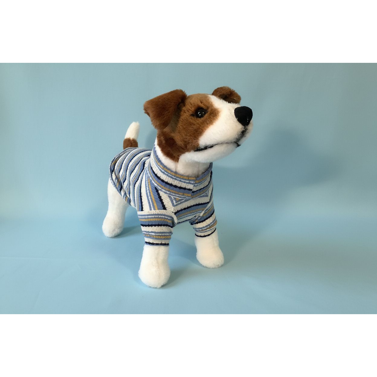 Stuffed dog toy wearing a striped outfit on a white background