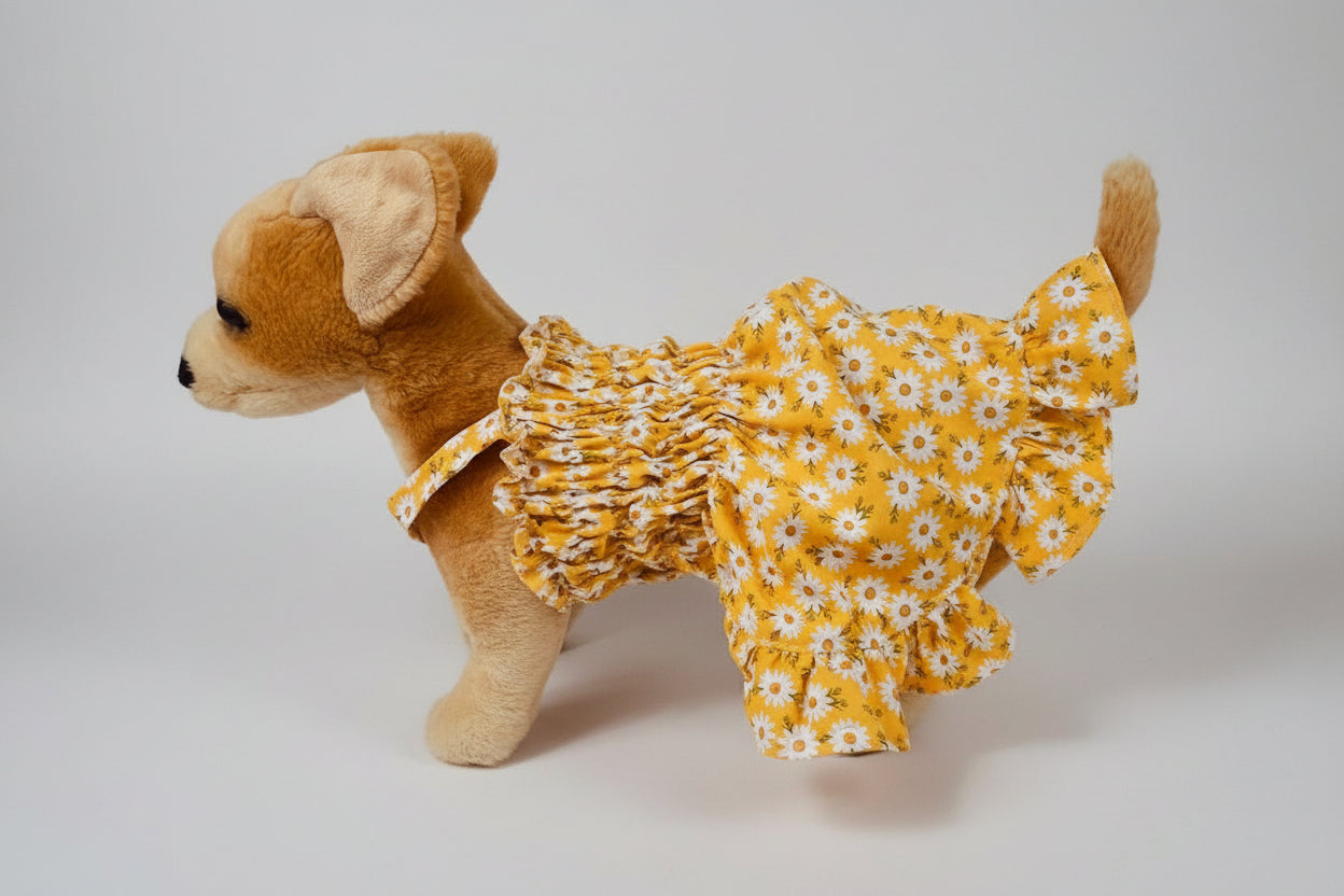 Stuffed dog toy wearing a yellow floral dress on a white background