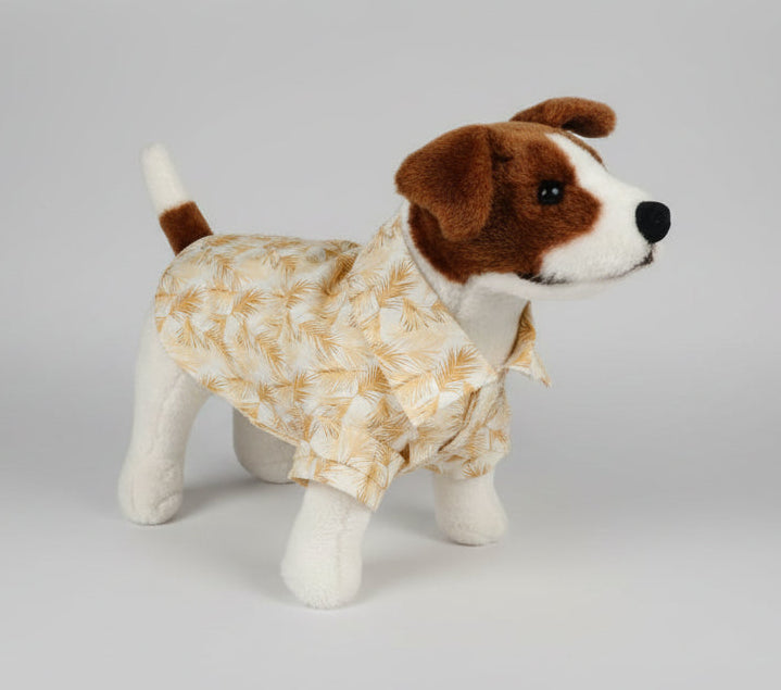 Stuffed dog toy wearing a yellow floral shirt on a white background