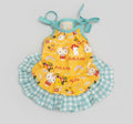 Yellow dress with Hello Kitty print and green checkered skirt on a pink surface
