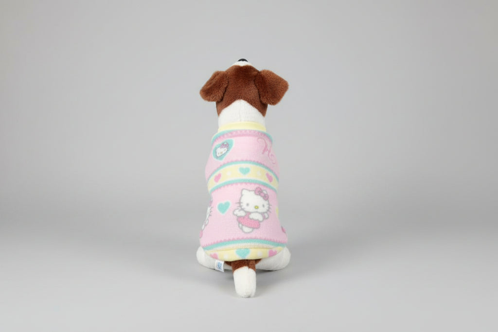 Small dog wearing a colorful long sleeve fleece hello kitty dog  sweater on a beige couch.