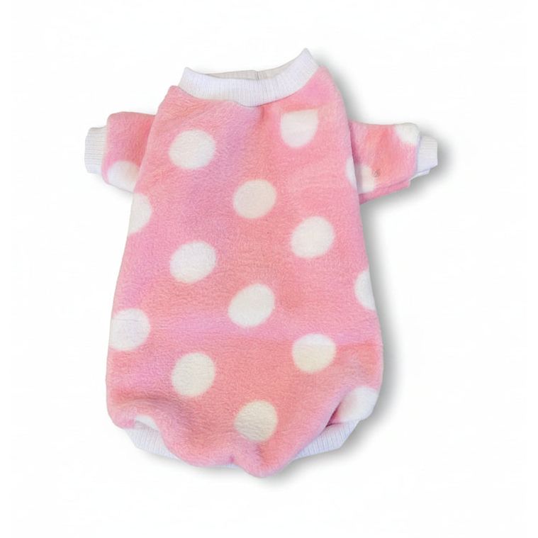 Pink fleece dog sweater with white polka dots on a beige textured surface
