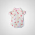 White pet sweater with pink floral pattern on a textured surface