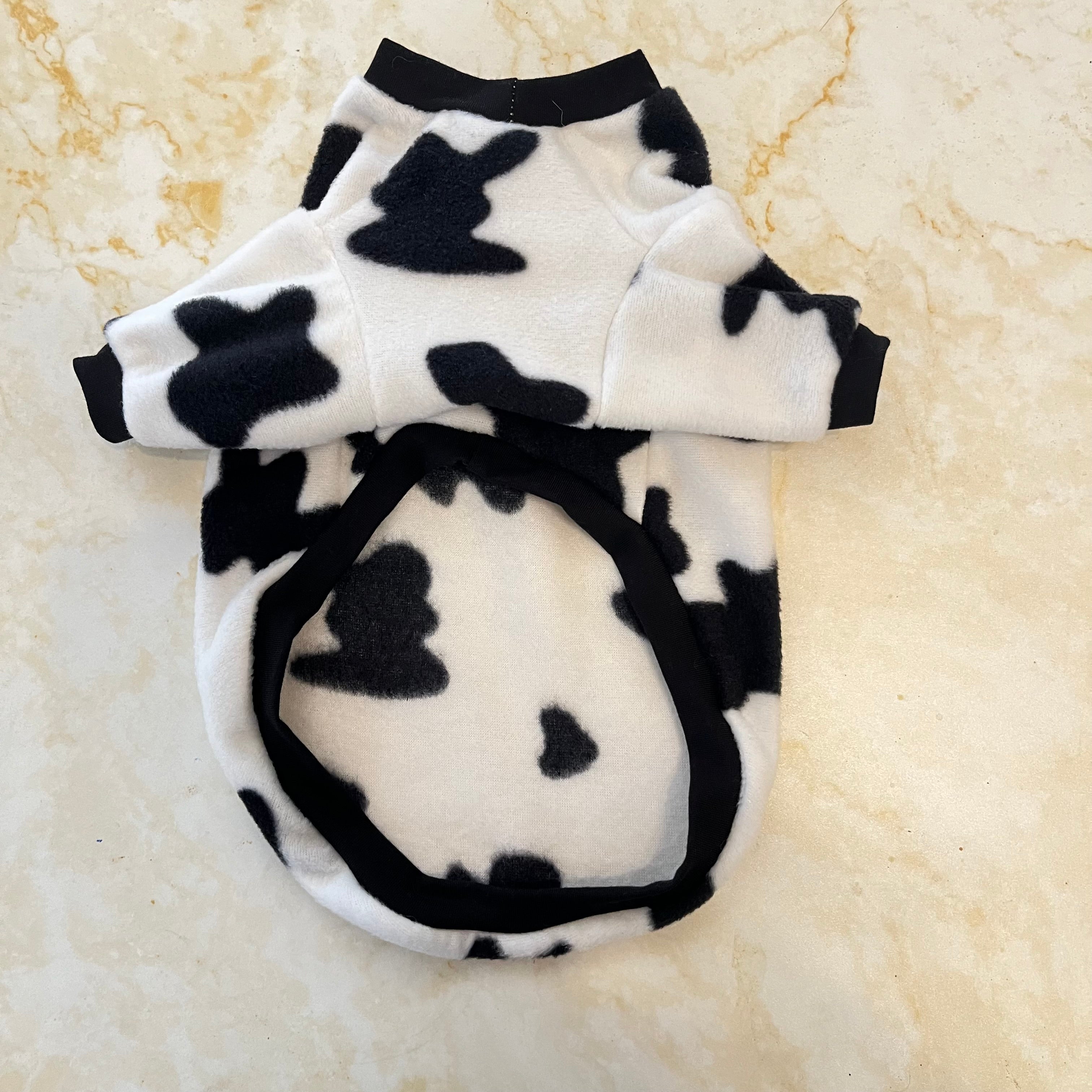 Black and white cow print pet sweater on a beige background