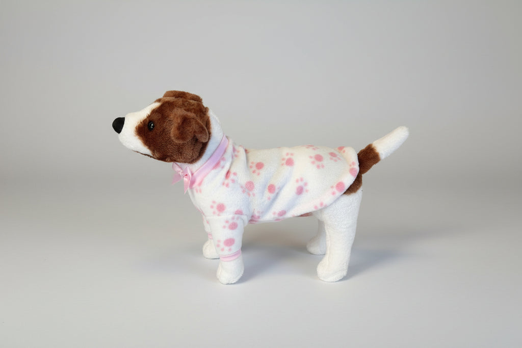 Stuffed dog toy wearing a pink outfit with paw prints on a beige couch.