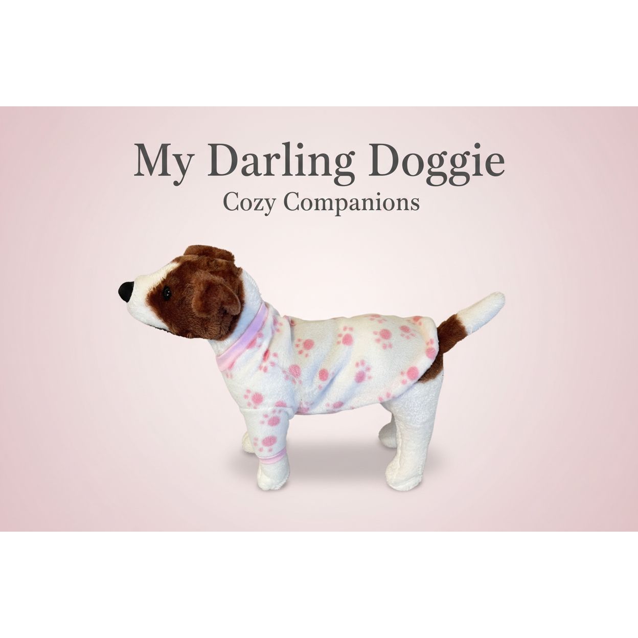 Stuffed dog toy wearing a pink outfit with paw prints on a beige couch.