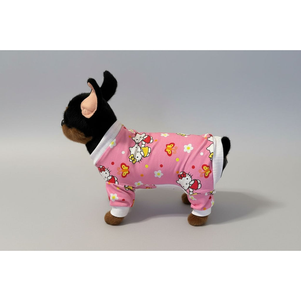 Small dog wearing a pink outfit with cartoon designs on a beige couch.