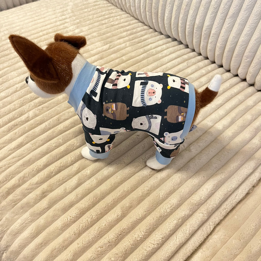 Small dog wearing a pajama with cartoon designs on a beige textured surface