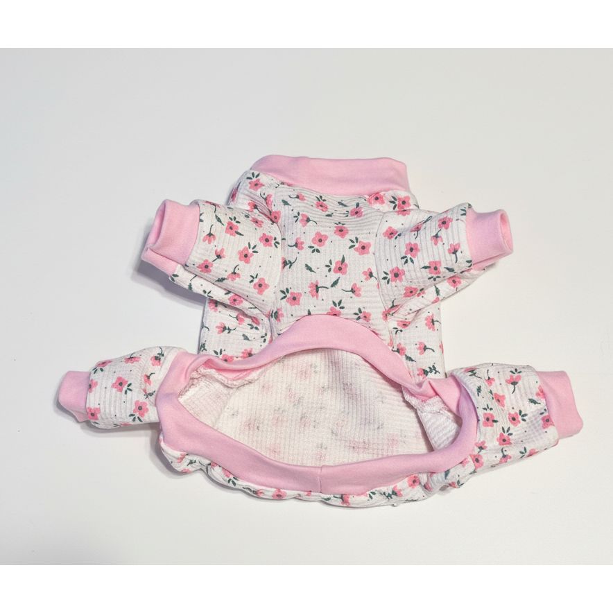 Floral-patterned dog pajamas with pink trim on a beige marble surface