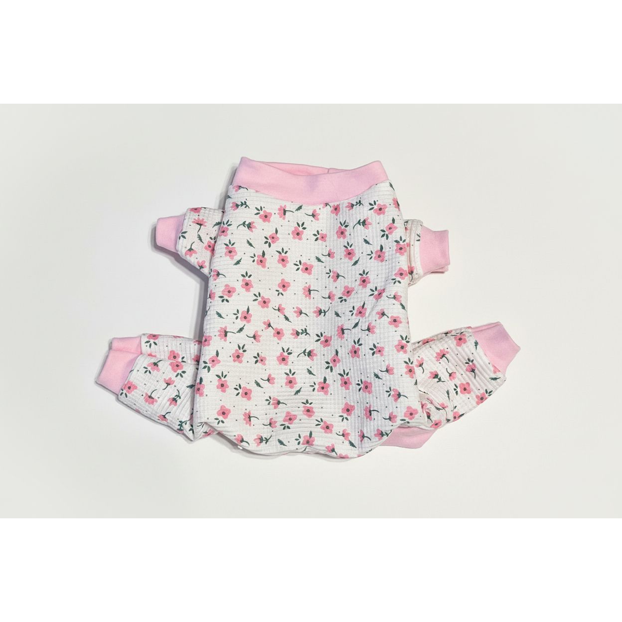 Floral dog pajamas with pink accents on a beige marble background