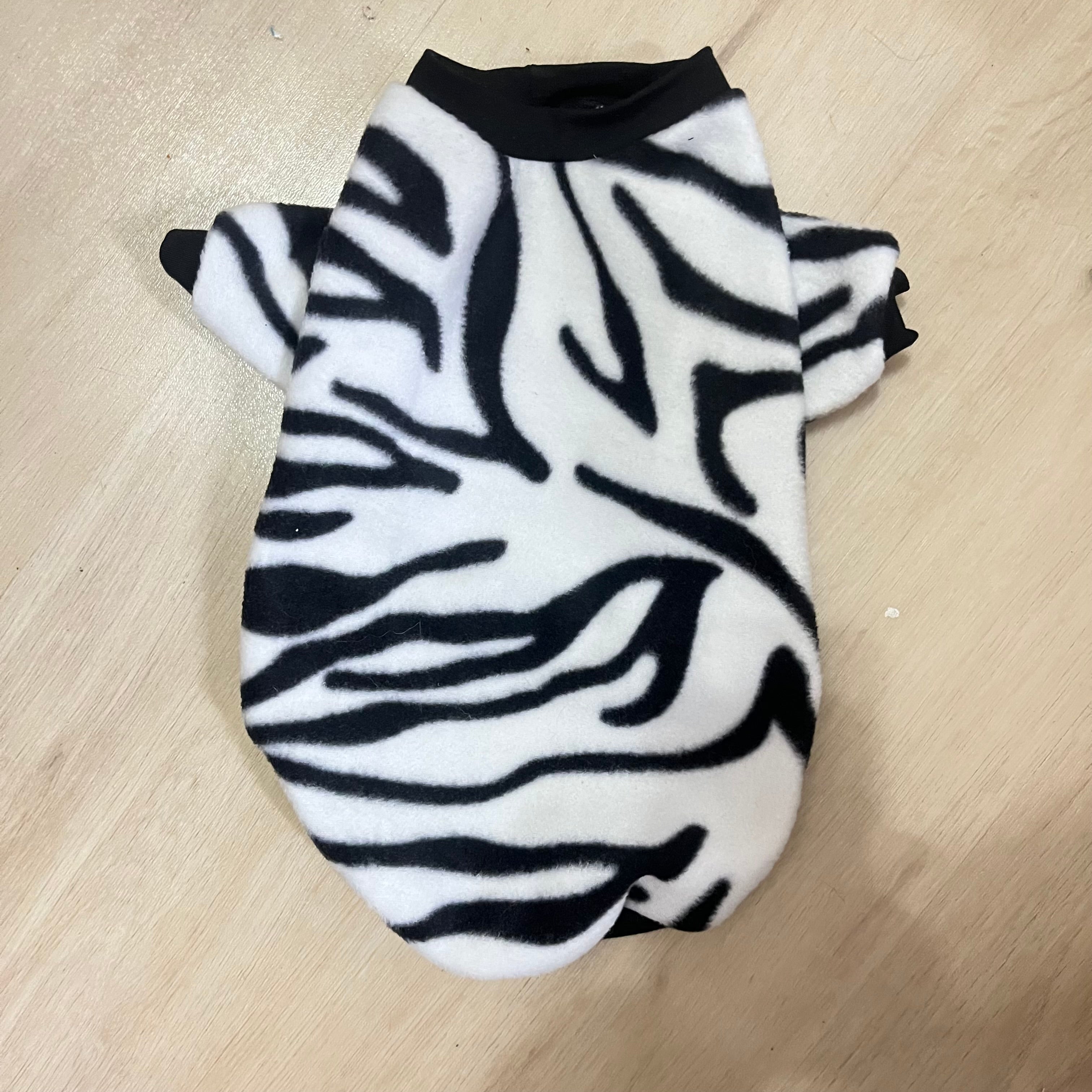 Black and white zebra print fleece dog sweater with black trim.