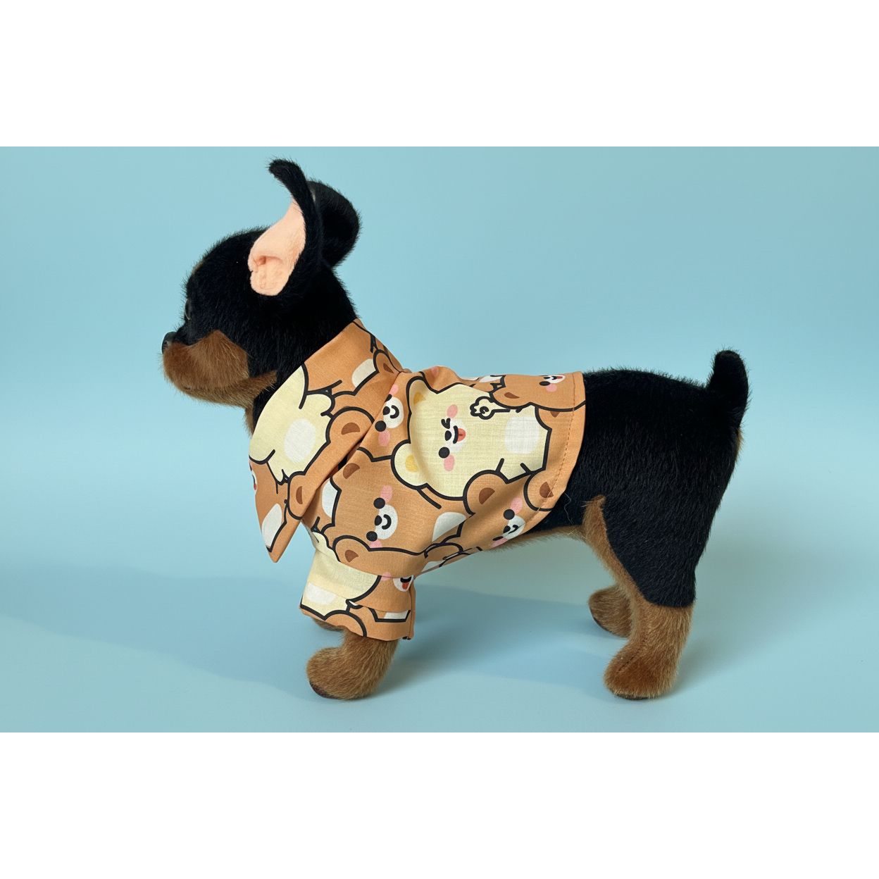 Small dog wearing a teddy bear-themed outfit on a white fabric background