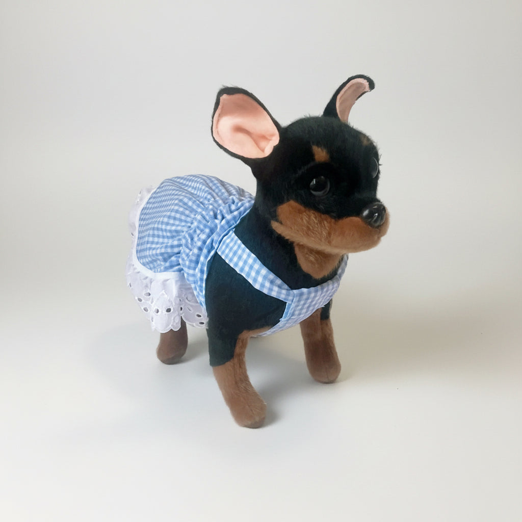 Stuffed dog toy wearing a blue checkered outfit on a white background