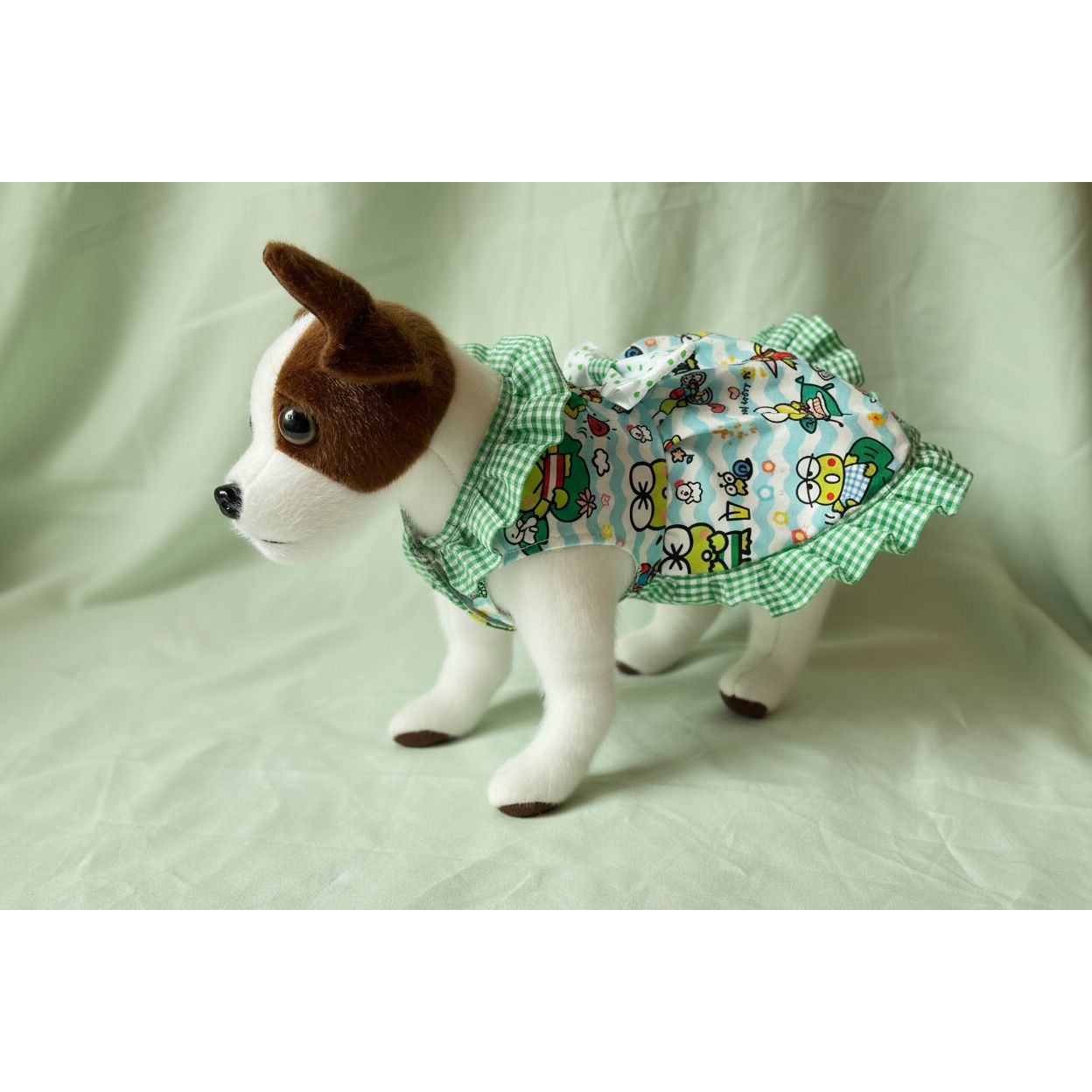 Small dog wearing a colorful dress with cartoon characters on a white background