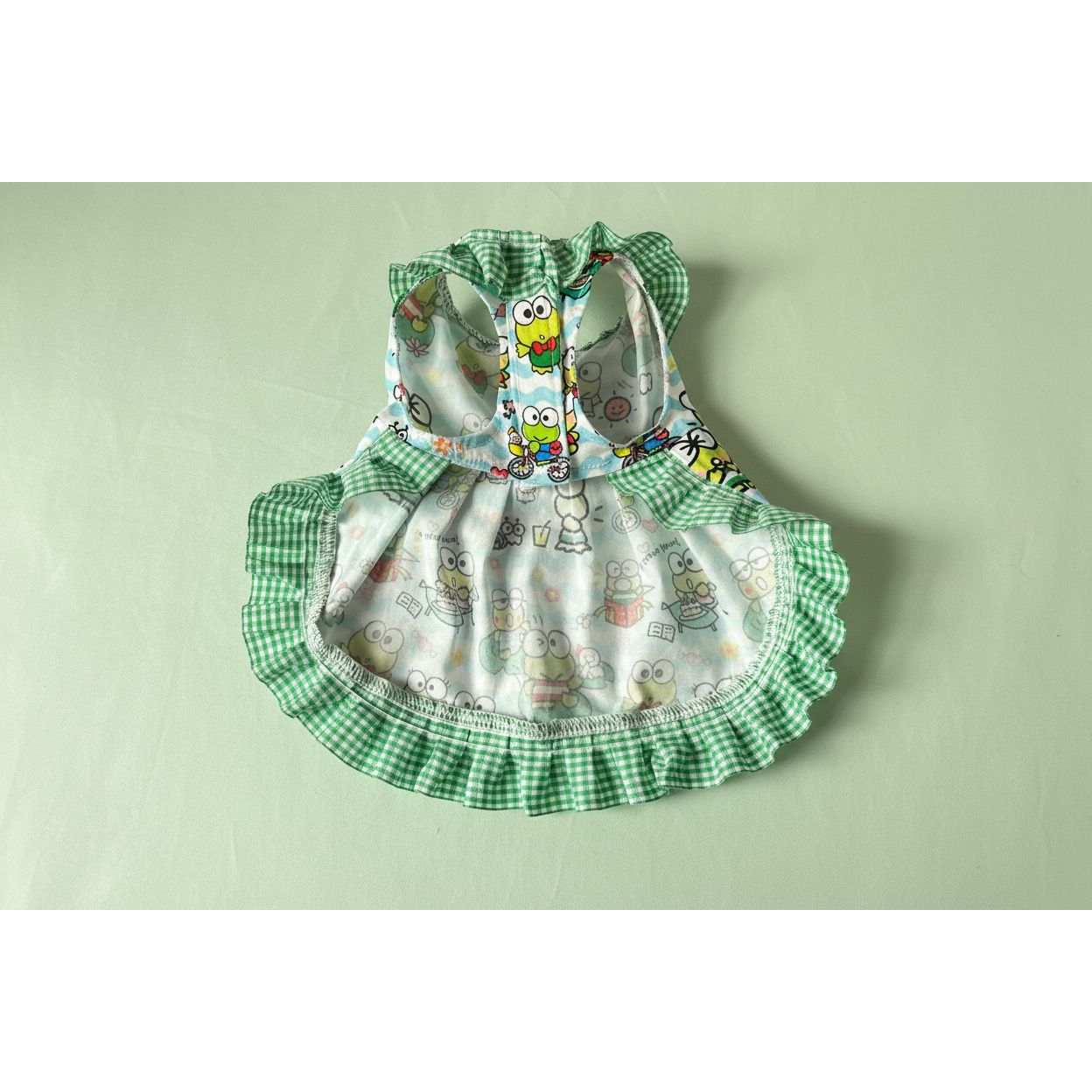 Children's dress with cartoon frog design on a white fabric background