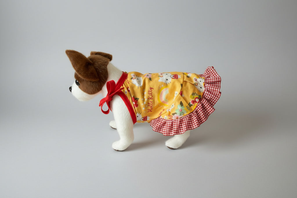 Real dog wearing a yellow dress with a red checkered skirt on a white background