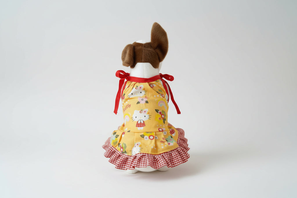 Small dog toy with a yellow dress featuring cartoon characters on a white background