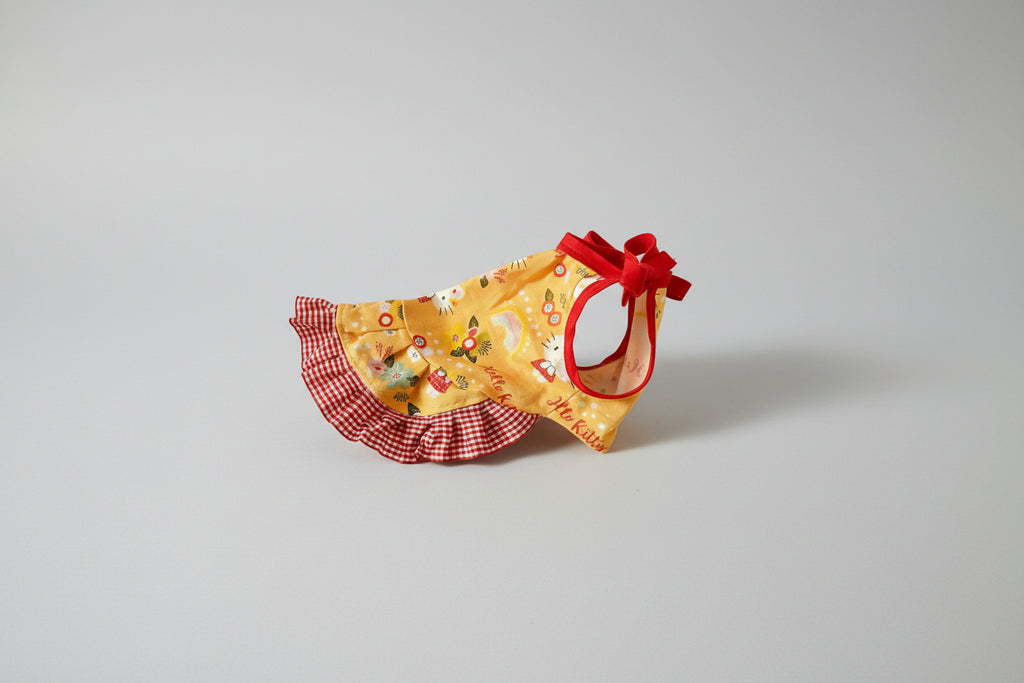 hello kitty dog dress with floral patterns and red accents on a white fabric background