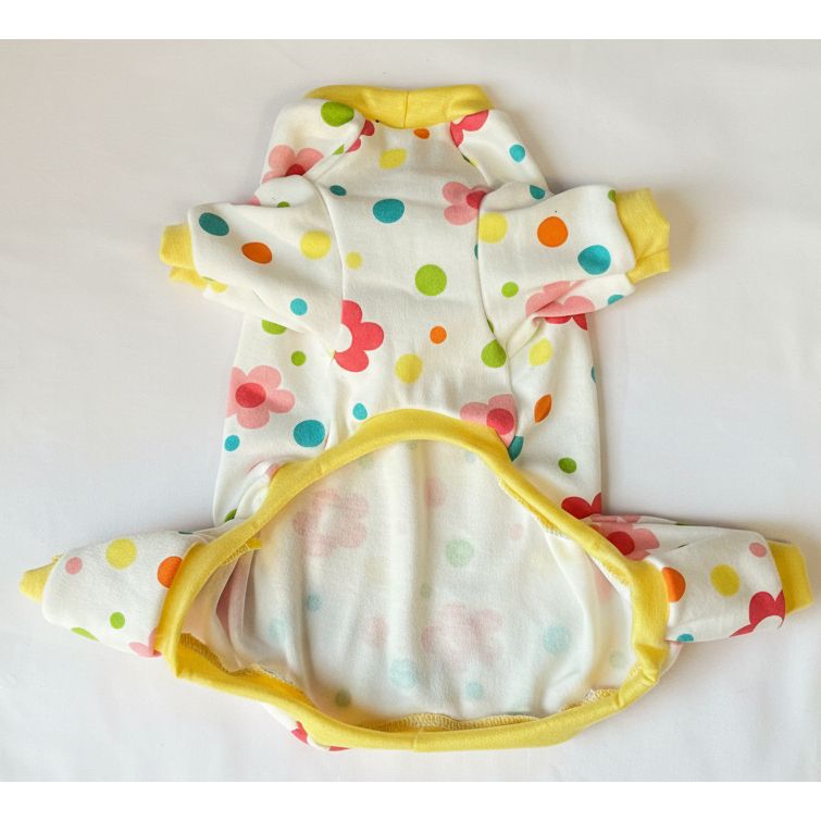 Colorful dog pajamas with polka dots and flowers on a pink surface