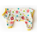 Colorful polka dot and flower patterned dog pajamas on a pink surface