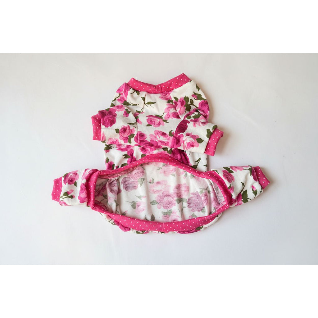 Floral dog pajamas outfit with pink trim on a beige surface