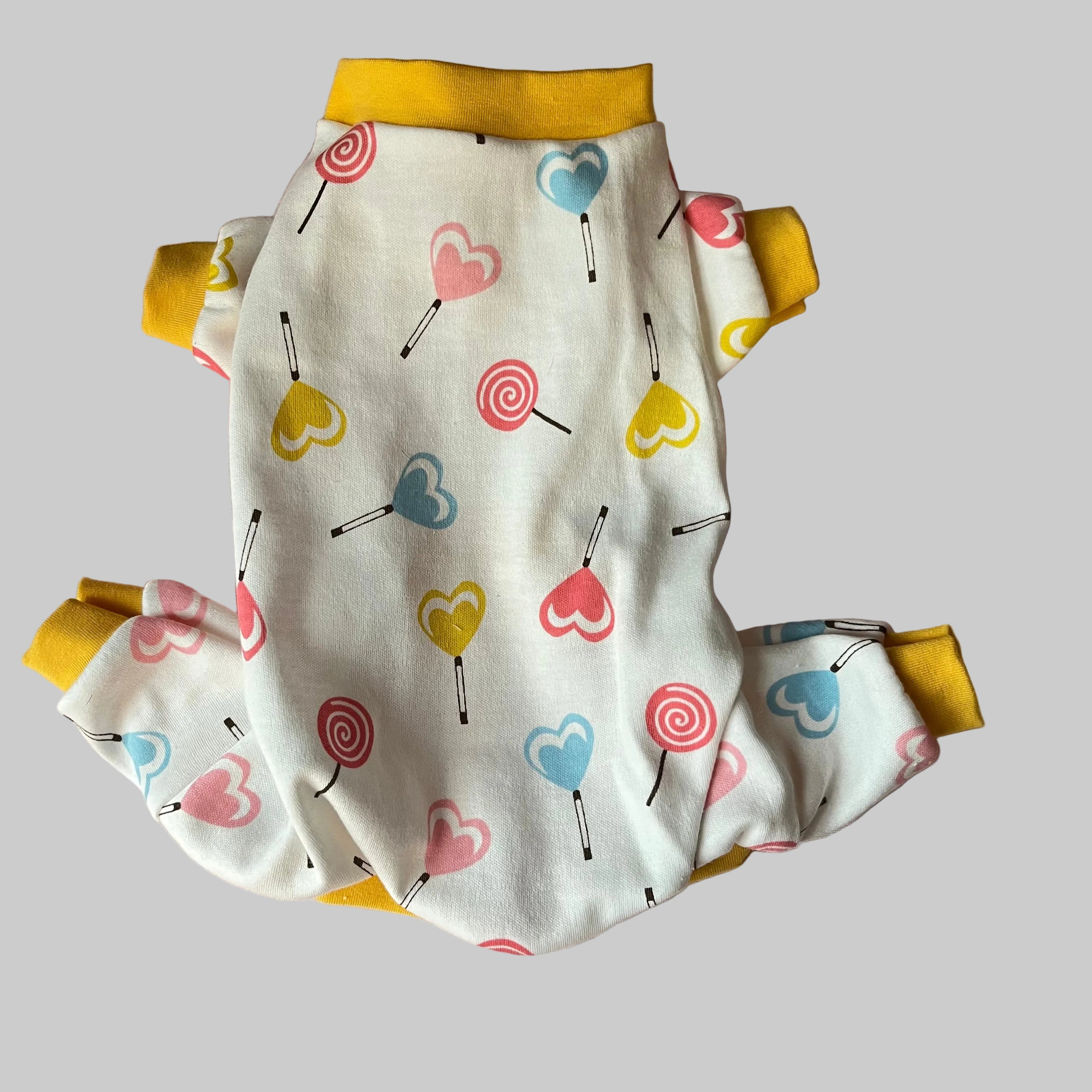 4 leg dog pajamas with colorful heart and lollipop pattern on a pink surface