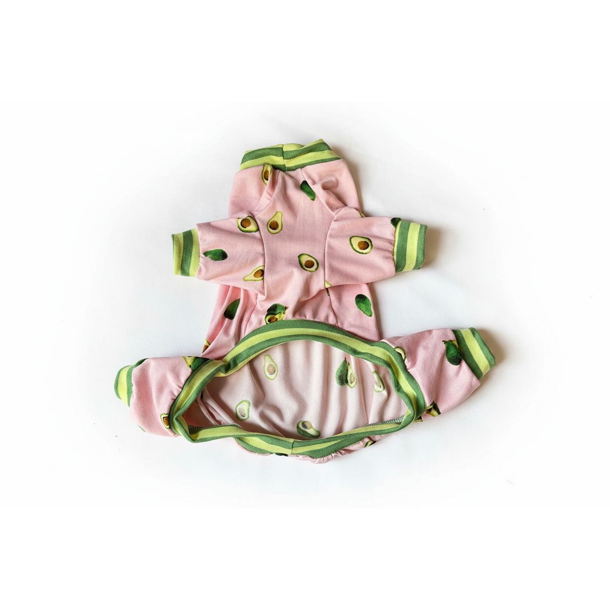 Pink dog pajamas with avocado pattern on a beige surface