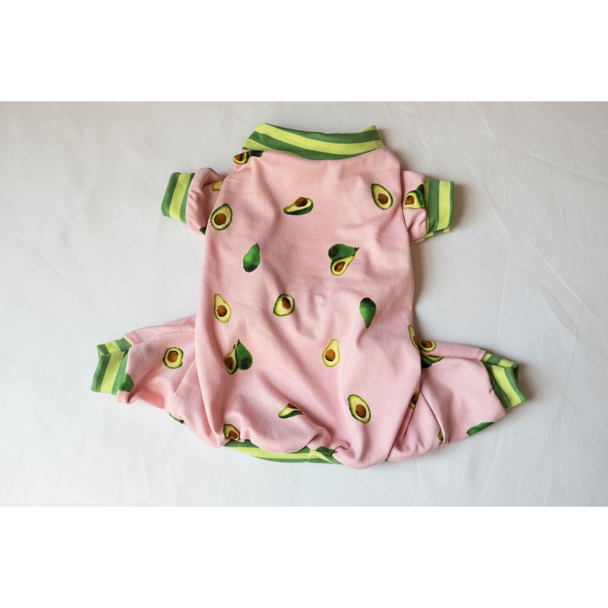 Pink dog pajamas with avocado pattern on a beige surface