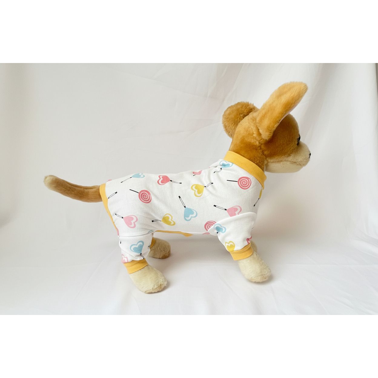 Plush dog toy wearing pajamas with a pattern on a white background