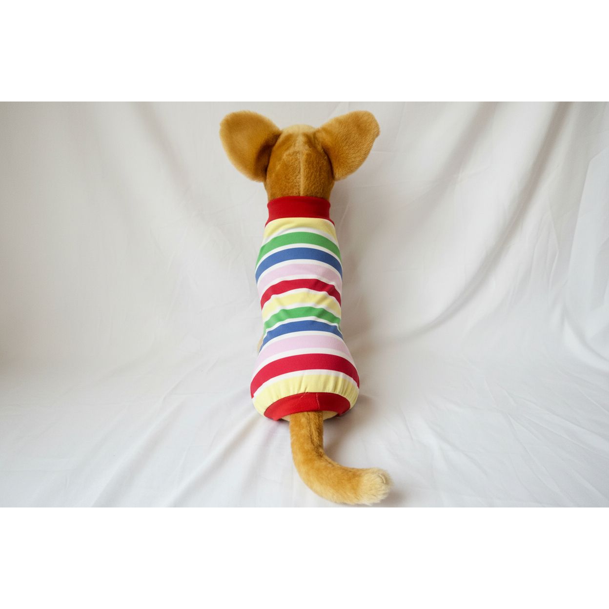 Stuffed animal toy with a rainbow striped shirt on a white background