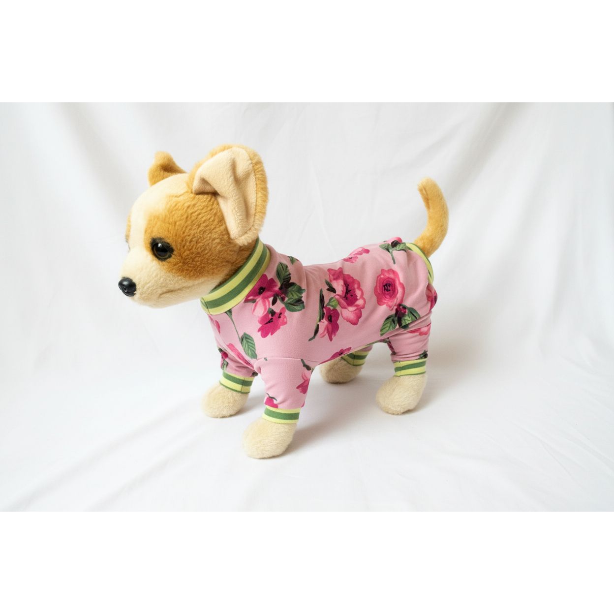 Stuffed dog toy wearing pink floral pajamas on a white background